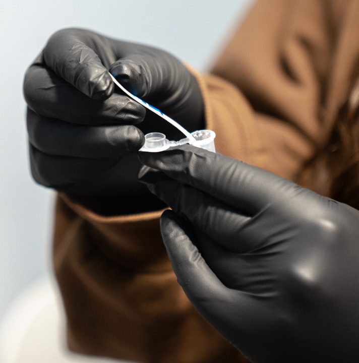 Gloved hands dip a test strip into a drug sample.