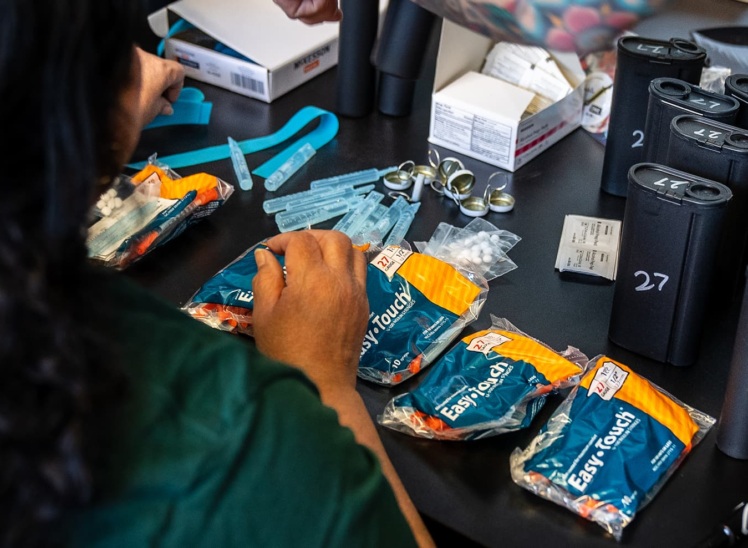 People assembling packets of supplies for safer drug use.