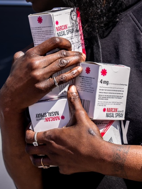 Closeup photo of a person holding multiple boxes of naloxone.