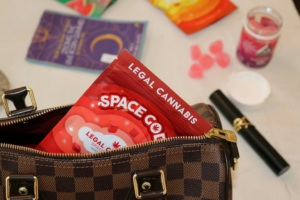 various marijuana products on a table, in the left corner a purse is open with a legal cannabis package peaking out 