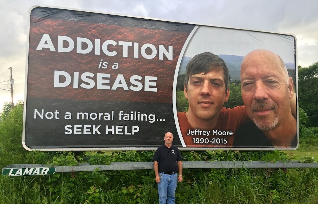 James Moore in front of the billboard he created
